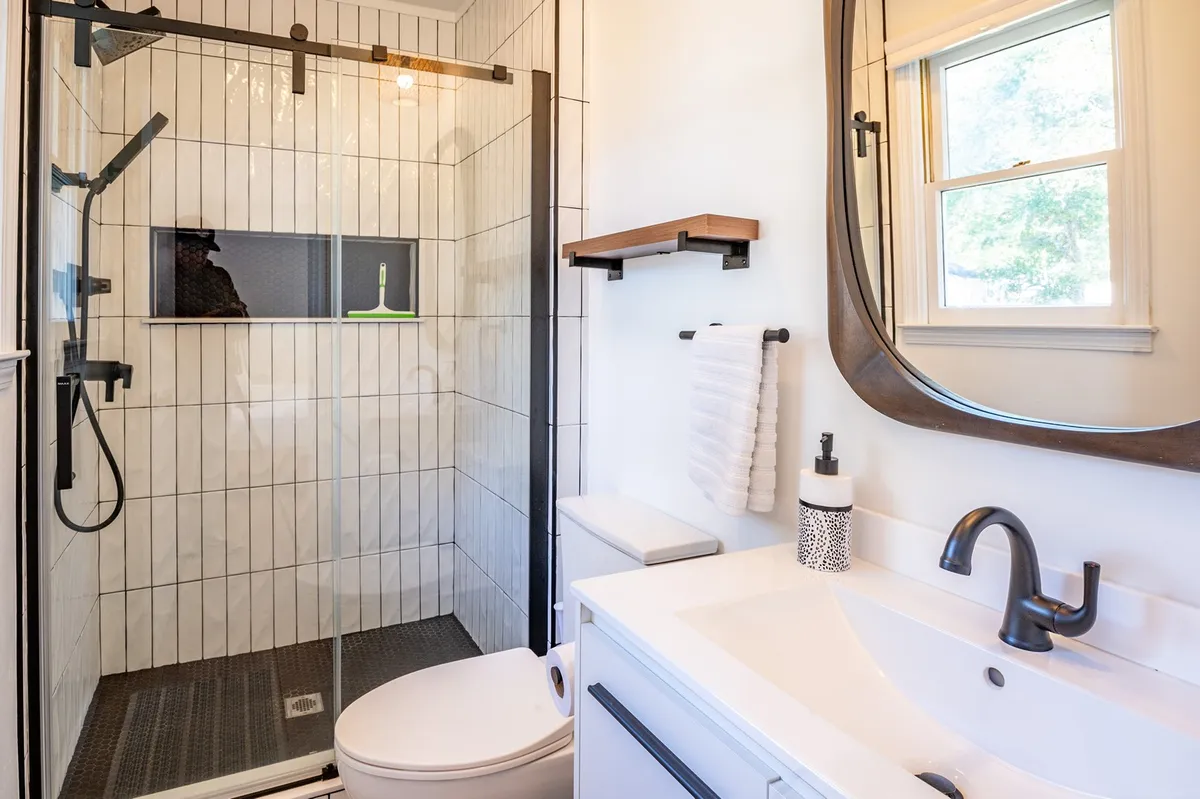 A modern bathroom with a spacious walk-in shower, double shower heads, a sleek vanity, and a large mirror. The design is bright, refreshing, and spa-like—inviting relaxation and self-care.
