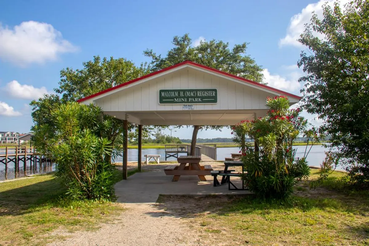 Featuring a pavilion with a red roof, picnic tables, and a waterfront view, this image captures the spirit of community events, outdoor gatherings, and sunset celebrations that define Oak Island’s summer festival scene.