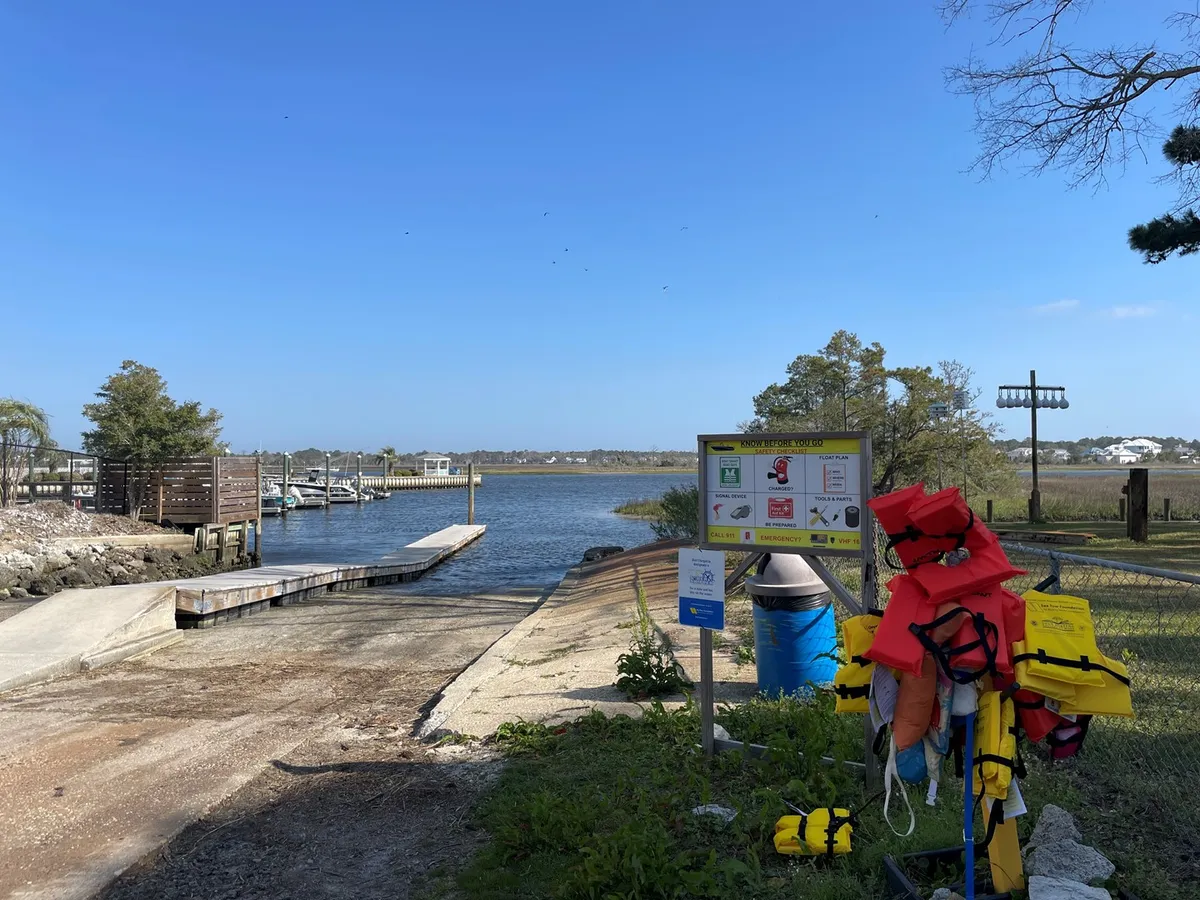 This image showcases a dock equipped with life jackets, an information sign, and a wide waterway stretching out beyond, inviting boating, kayaking, and fishing. The scene captures the sense of adventure and direct access to water activities that the property encourages.