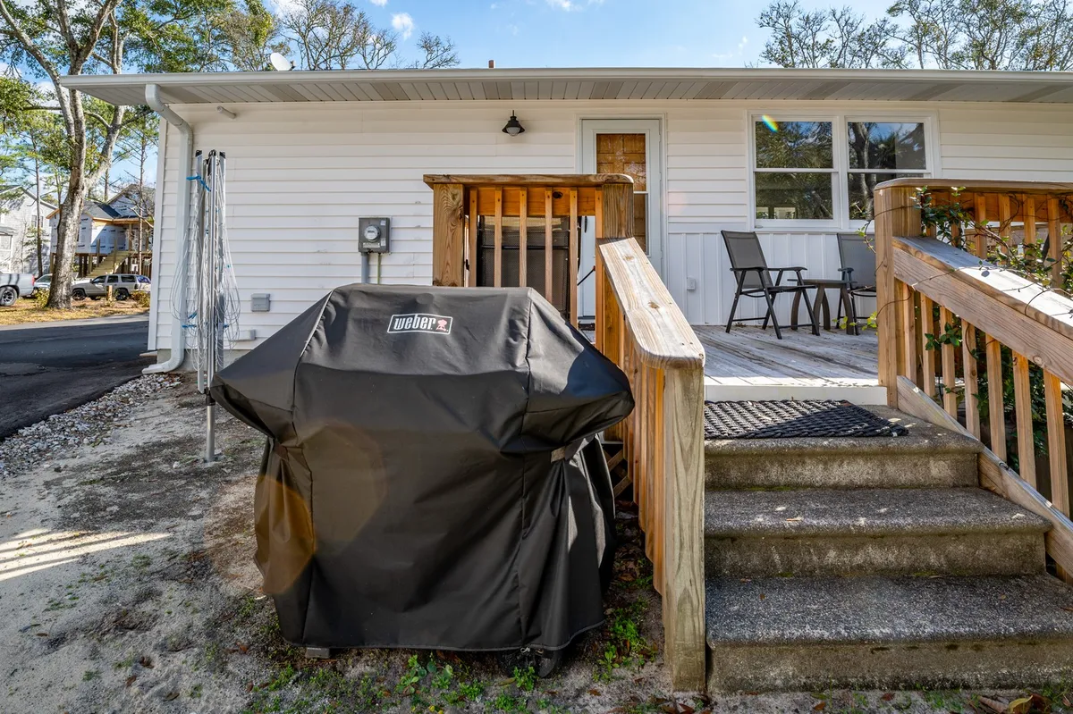 This exterior image highlights a grill positioned near inviting wooden steps and the home's entryway, offering a glimpse of a relaxed outdoor dining space ideal for gatherings after a day of outdoor activities.